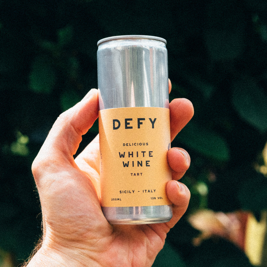 Hand holding up a can of DEFY vegan Sicilian white wine